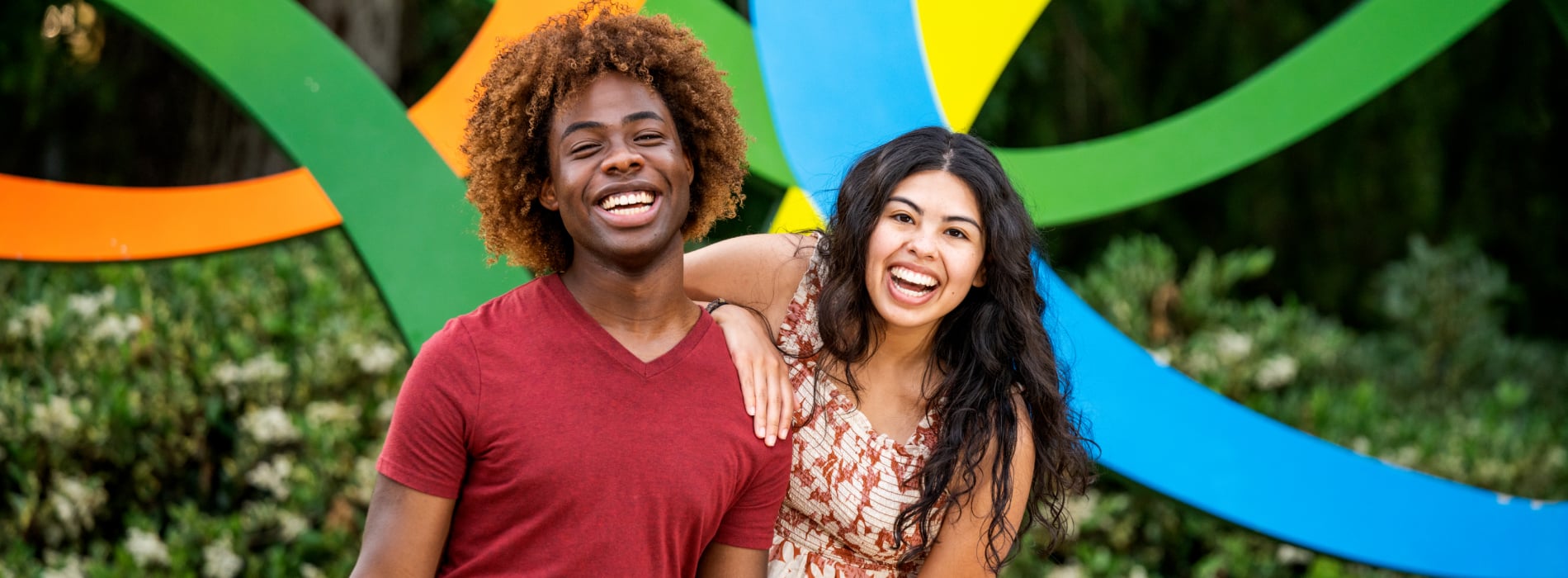 Two young adults in front of the Busch Gardens logo